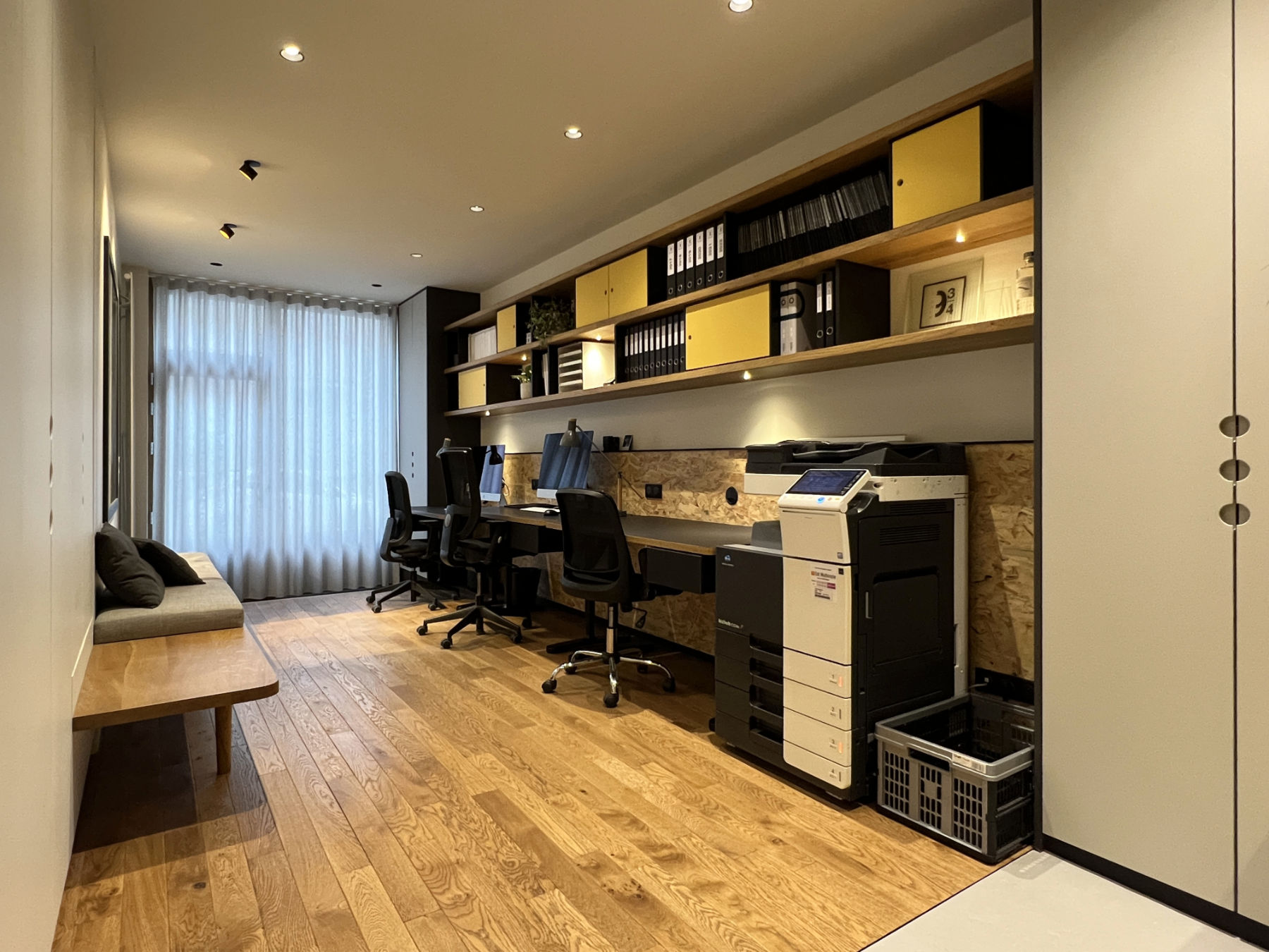 Bureaux ambiance chaleureuse avec sol parquet et étagères bois et rangements jaunes et noirs