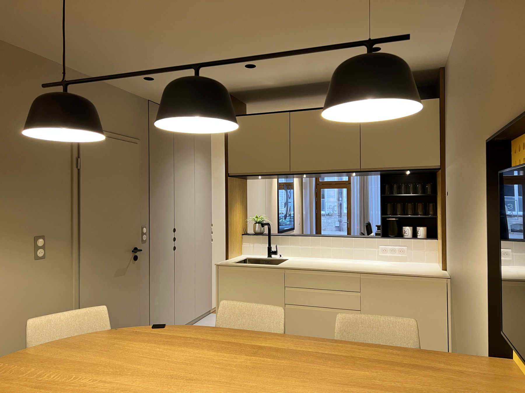 Kitchenette blanche élégante vue depuis une table de réunion ou de repas