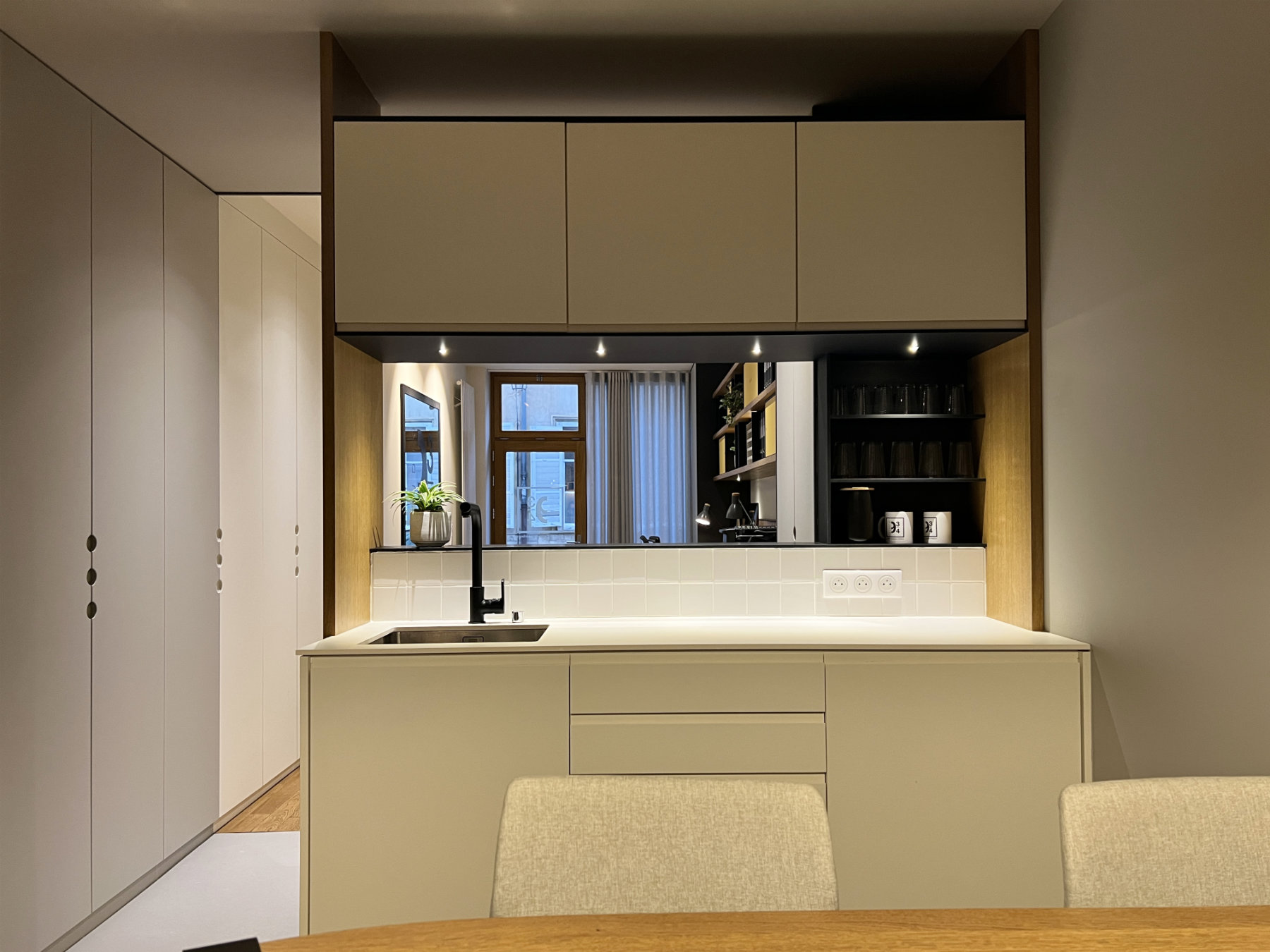 Kitchenette blanche élégante vue depuis une table de réunion ou de repas