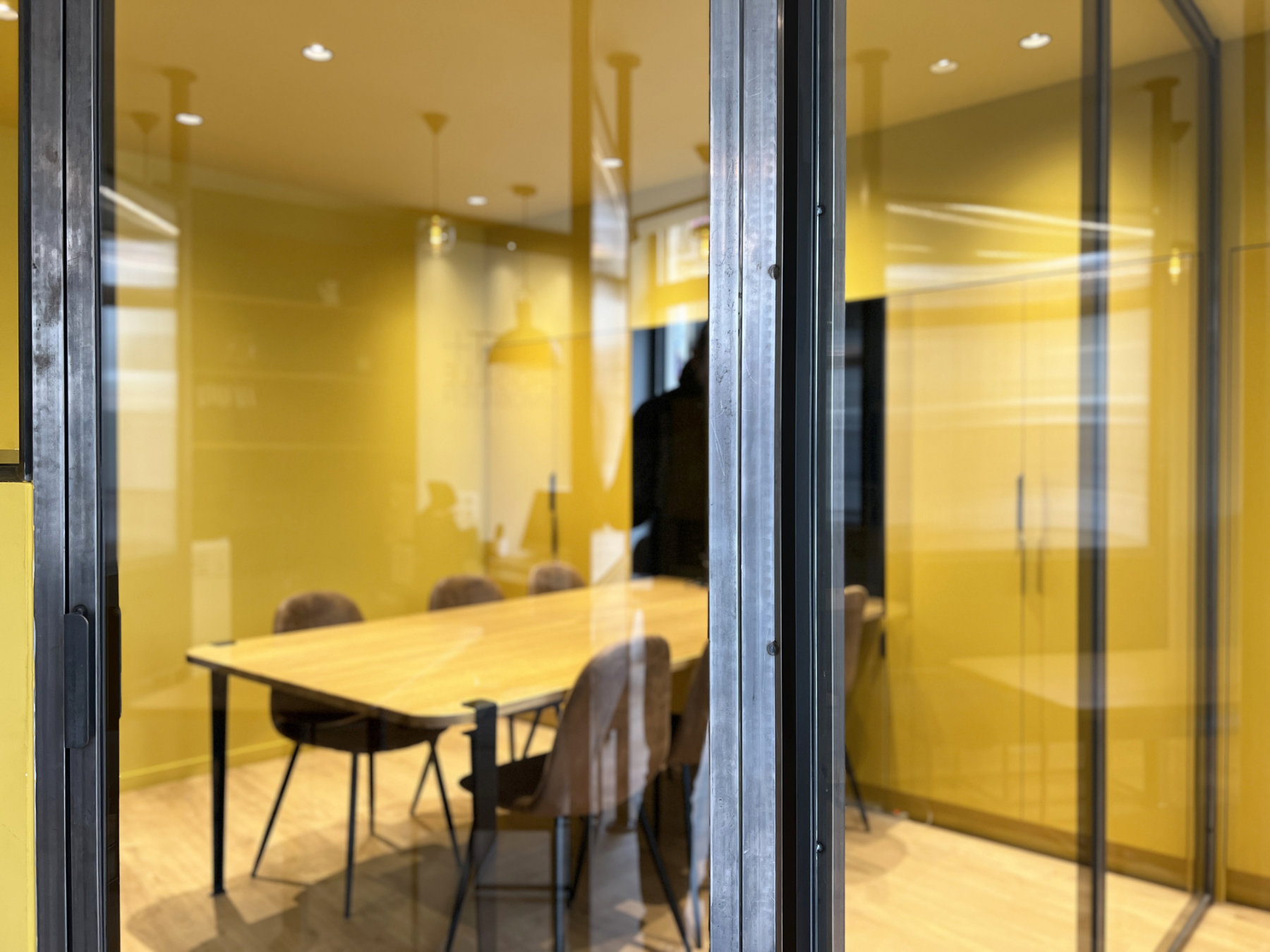 salle de réunion entièrement jaune vue en arrière plan derrière châssis vitré